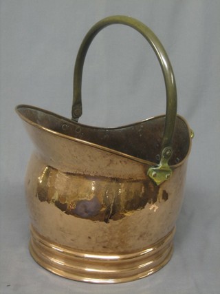 A copper helmet shaped coal scuttle with brass swing handle 