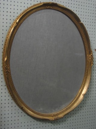 An oval bevelled plate wall mirror contained in a decorative gilt frame 26"