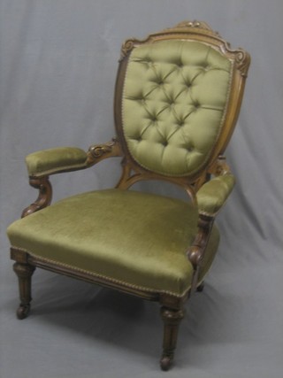 A Victorian carved walnut open arm chair the back upholstered in buttoned material, raised on turned and fluted supports