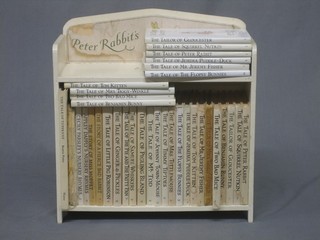 A collection of various Beatrix Potter books contained in a small painted bookcase