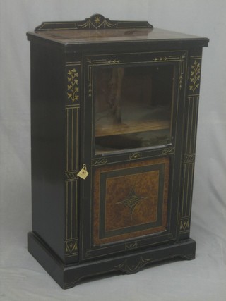 A Victorian ebonised and amboyna music cabinet, fitted shelves enclosed by a glazed panelled door 24"