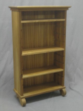 A Victorian style bleached mahogany bookcase fitted adjustable shelves, raised on scrolled supports 22" 