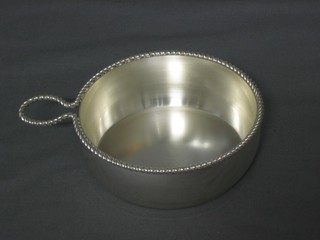 A circular silver plated wine taster with rope edge border