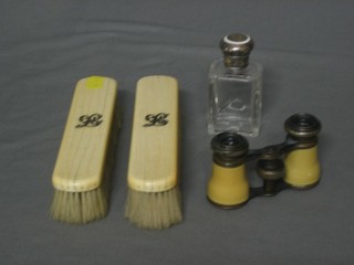 A pair of ivory backed clothes brushes, a square glass dressing table jar with silver lid and a small pair of ivory finished opera glasses