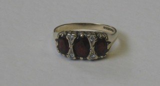 A 9ct gold dress ring set 3 oval cut garnets supported by diamonds