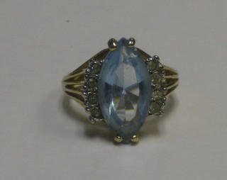A gold coloured dress ring set a boat shaped blue stone supported by white stones  