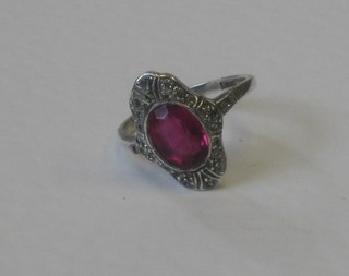 A lady's 1920's dress ring set an oval red stone surrounded by "diamonds"