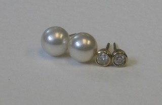 A pair of diamond ear studs and a pair of pearl ear studs
