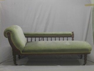 An Edwardian carved oak show frame chaise longue with bobbin turned decoration, the back upholstered green material, raised on turned supports