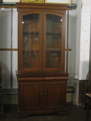 A mahogany display cabinet on cabinet, the upper section with moulded cornice, the interior fitted glazed shelves enclosed by glazed panelled doors, the base fitted 2 drawers above a double cupboard enclosed by panelled doors, raised on bracket feet 38" 