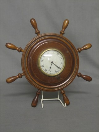 An 8 day wall clock with silvered dial by Smiths contained in a model wooden ships wheel