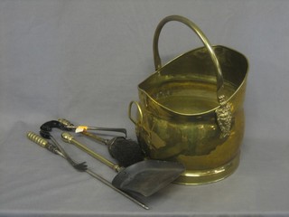 A brass helmet shaped coal scuttle together with a brass coal shovel, brush, poker and tongs