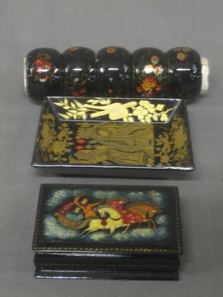 A Russian lacquered trinket box painted a sleigh scene 3 1/2" signed, do. tray decorated King and Queen of Diamonds 4 1/2" and 5 Russian lacquered napkin rings