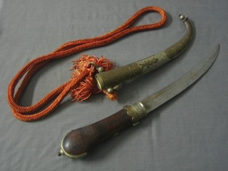 An Eastern style Jambuka with 9 1/2" blade contained in an an engraved brass scabbard