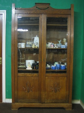 An oak Arts & Crafts bookcase with raised back, fitted adjustable shelves enclosed by glazed panelled doors 47"
