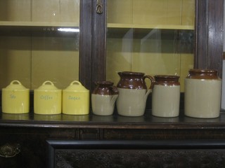 3 oval yellow glazed pottery kitchen storage jars marked Tea, Sugar and Coffee, 2 brown glazed jugs and 2 bread crocks