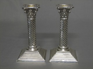 A pair of Victorian silver candlesticks with Corinthian capitals with spiral turned columns and raised on stepped bases, London 1894, bases inscribed 6 1/2" high
