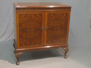 A Queen Anne style walnut cabinet enclosed by panelled doors, raised on cabriole supports 34"
