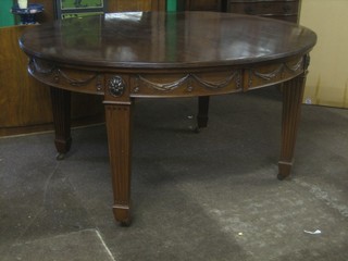 A handsome Edwardian, Georgian style mahogany extending dining table, the frieze carved swags raised on square fluted tapering supports, complete with 2 extra leaves