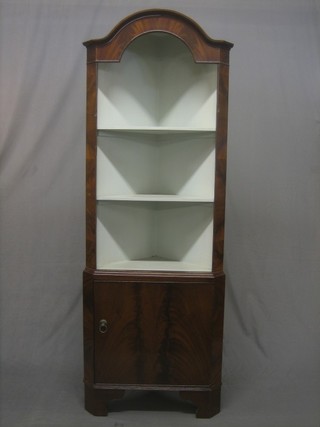 A Georgian style mahogany dome shaped double corner cabinet, the upper section fitted shelves,  the base fitted a cupboard enclosed by panelled doors, raised on bracket feet 27"