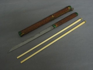 An Oriental eating set comprising a knife and 2 carved ivory chop sticks, contained in a heavily carved hardwood case 