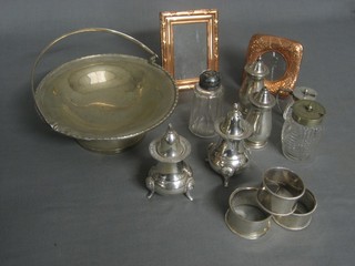 A circular silver plated dish with swing handle, 3 napkin rings, 2 small easel photograph frames etc