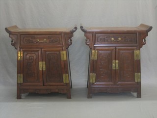 A pair of Oriental carved Padouk wood cabinets fitted a drawer above a double cupboard, carved throughout 30"