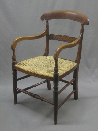 A 19th Century mahogany bar back open arm chair with carved mid rail and woven rush seat, raised on turned supports