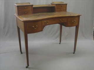 An Edwardian inlaid mahogany writing table with inset tooled leather writing surface, the raised back with brass three-quarter gallery fitted 4 short drawers, the base fitted 1 long and 2 short drawers, raised on square tapering supports 38"