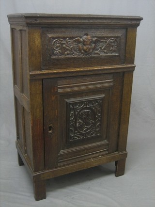 An oak cabinet, the upper section with fall front, the base fitted a cupboard enclosed by an antique panelled door 26"