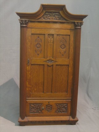 A carved oak corner cabinet with raised cornice, fitted shelves enclosed by a panelled door, the base fitted a drawer flanked by a pair of turned and reeded columns with Ionic capitals 24"