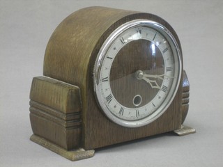 A 1930's mantel clock with silvered dial and Roman numerals contained in an arch shaped oak case