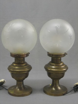 A pair of brass oil lamps with etched glass shades