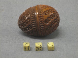 A carved wooden egg containing 3 bone dice 2"
