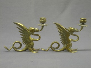 A pair of brass candlesticks in the form of griffins 7"
