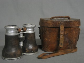 A pair of vintage binoculars contained in a brown leather case