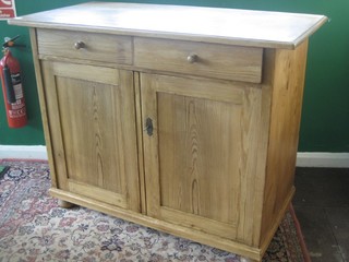 A Continental stripped and polished pine cabinet fitted 2 drawers above a double cupboard enclosed by panelled doors