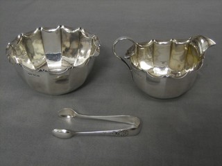 An Edwardian circular silver sugar bowl and matching cream jug, Sheffield 1907 5 ozs together with a pair of silver plated sugar tongs