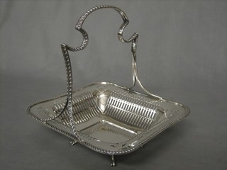 A handsome square pierced silver basket with ribbon work handle, raised on 4 hoof supports, London 1913 by the Goldsmiths & Silversmiths Co. 15 ozs