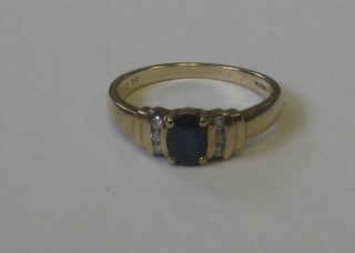 A 9ct gold dress ring set an oval cut sapphire supported by 6 diamonds to the shoulders