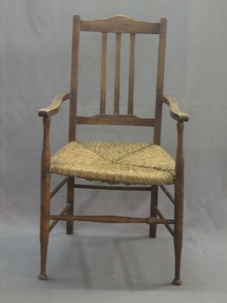 A bleached mahogany stick and rail back carver chair with woven rush seat, raised on turned supports