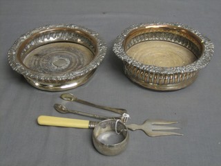 A pair of embossed silver plated bottle coasters, a silver plated napkin ring, a bread fork and a pair of silver plated sugar tongs