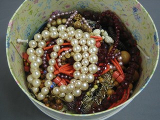 A circular box containing a collection of costume jewellery