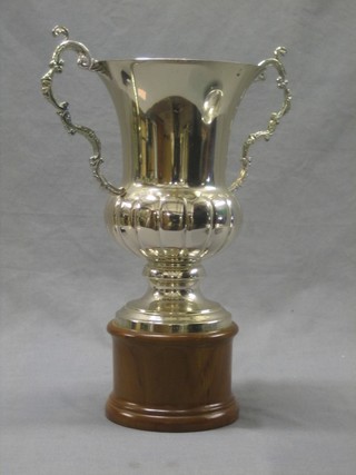 A large silver plated twin handled trophy cup raised on a wooden socle base 10"