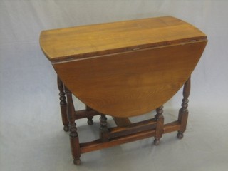 An elm oval drop flap gateleg dining table raised on turned and block supports 36"