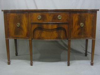 A Georgian style inlaid mahogany sideboard of serpentine outline, fitted 2 drawers flanked by a pair of cupboards, raised on square tapering supports ending in spade feet 60"