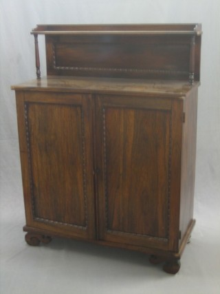 A Regency rosewood chiffonier with raised back, the base fitted 3 long drawers above cupboards enclosed by panelled doors, raised on scrolled supports 37"