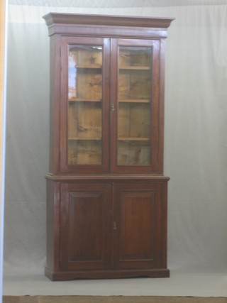 A Victorian walnut bookcase on cabinet, the upper section with moulded cornice, the interior fitted shelves enclosed by glazed panelled doors, the base fitted a cupboard enclosed by panelled doors, raised on a platform base 38"