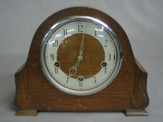 A chiming mantel clock with silvered chapter ring and Arabic numerals contained in an oak arch shaped case
