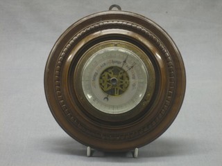 An aneroid barometer with silvered dial contained in a circular carved walnut case 8"